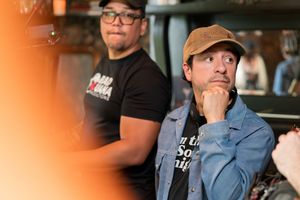 Two production crew members collaborate during filming in an indoor location.