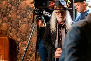 Camera operator working with vintage film equipment in atmospheric setting.