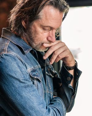 Person in denim jacket looking contemplative in natural lighting.