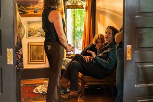 Three people having an intimate conversation in a dimly lit room with vintage decor and warm lighting.