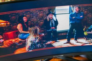 Monitor displaying scene of people in casual indoor setting during film production.
