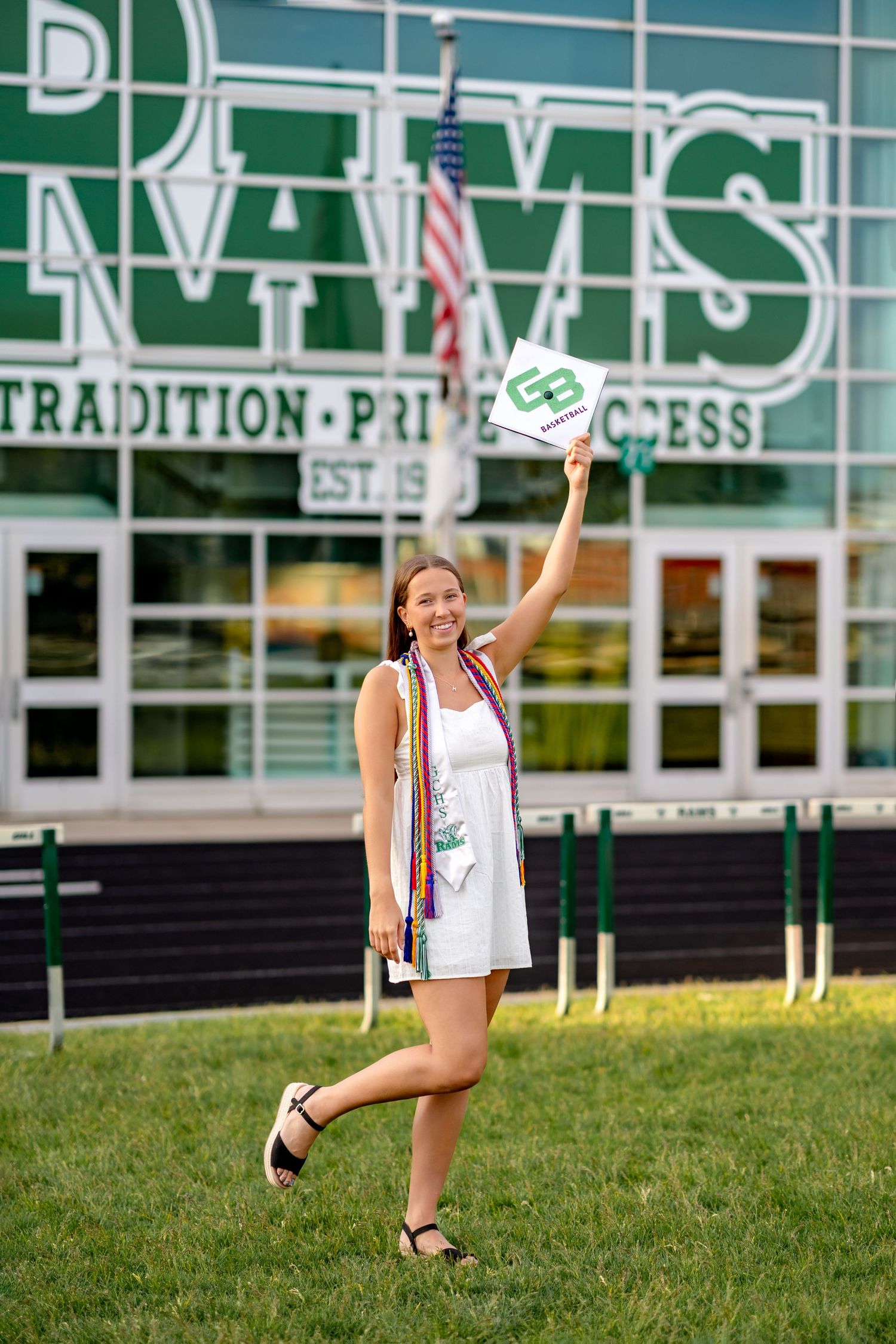 Graduate celebrating in front of school building with American flag waving diploma in the air at RVMS.