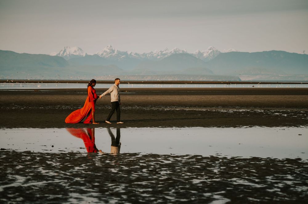 Maternity portrait of couple holding hands along kye bay beach with reflection in ocean sunset Comox Valley Vancouver Island photographer