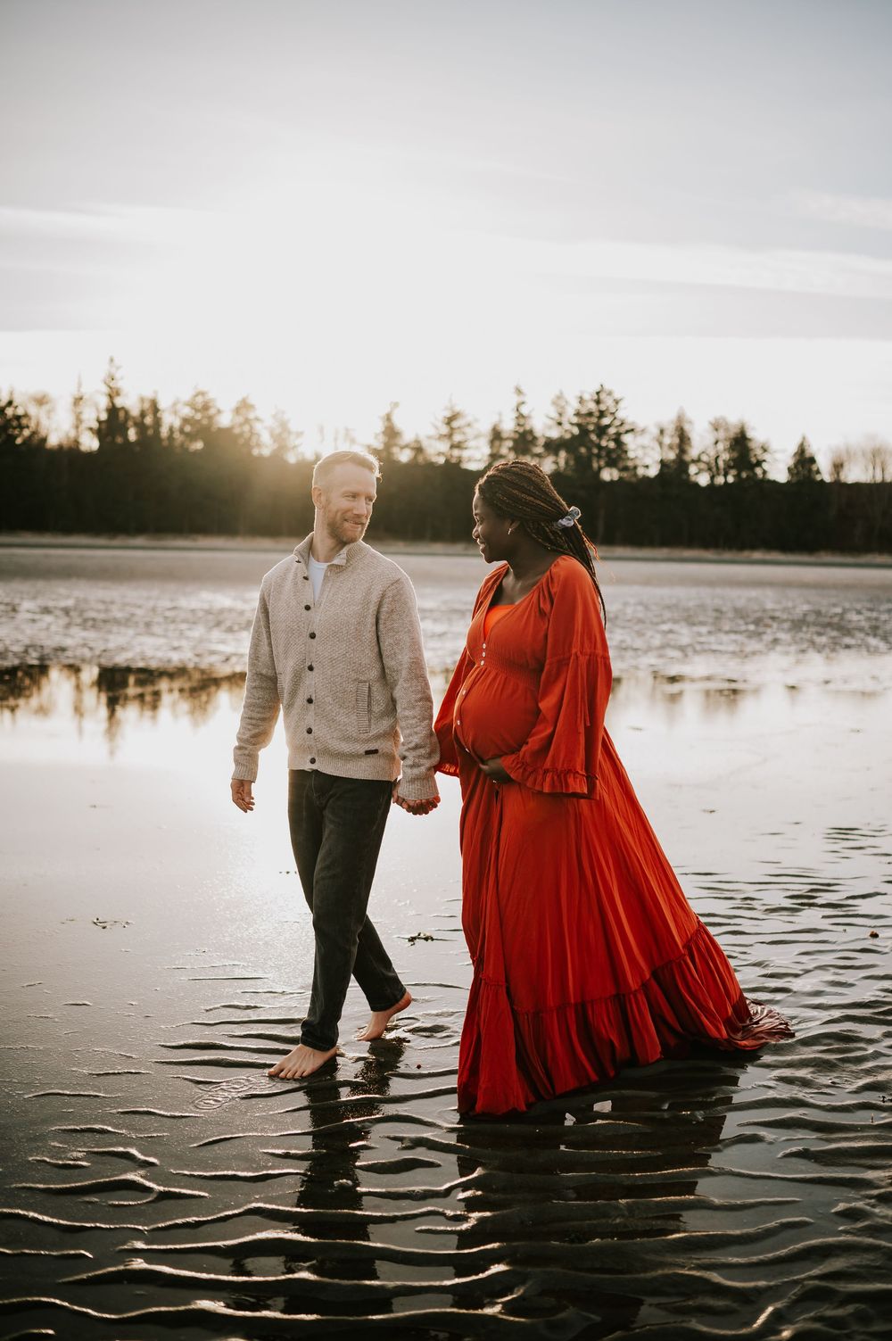 Maternity portrait of couple holding hands along kye bay beach in red dress during sunset Comox Valley Vancouver Island photographer