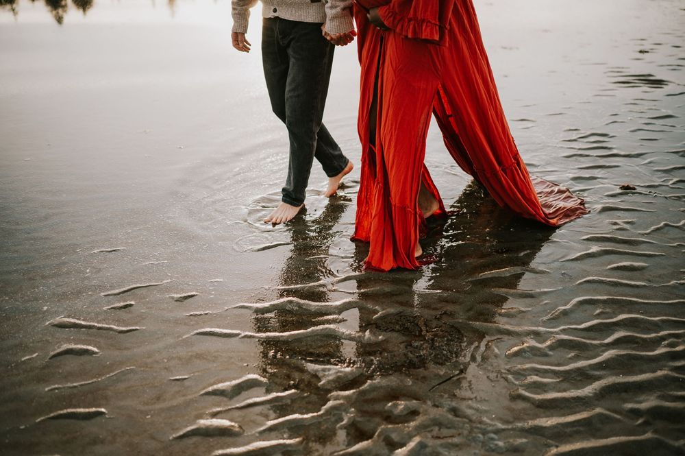 Maternity portrait of couple feet walking through ocean kye bay beach in red dress during sunset Comox Valley Vancouver Island photographer