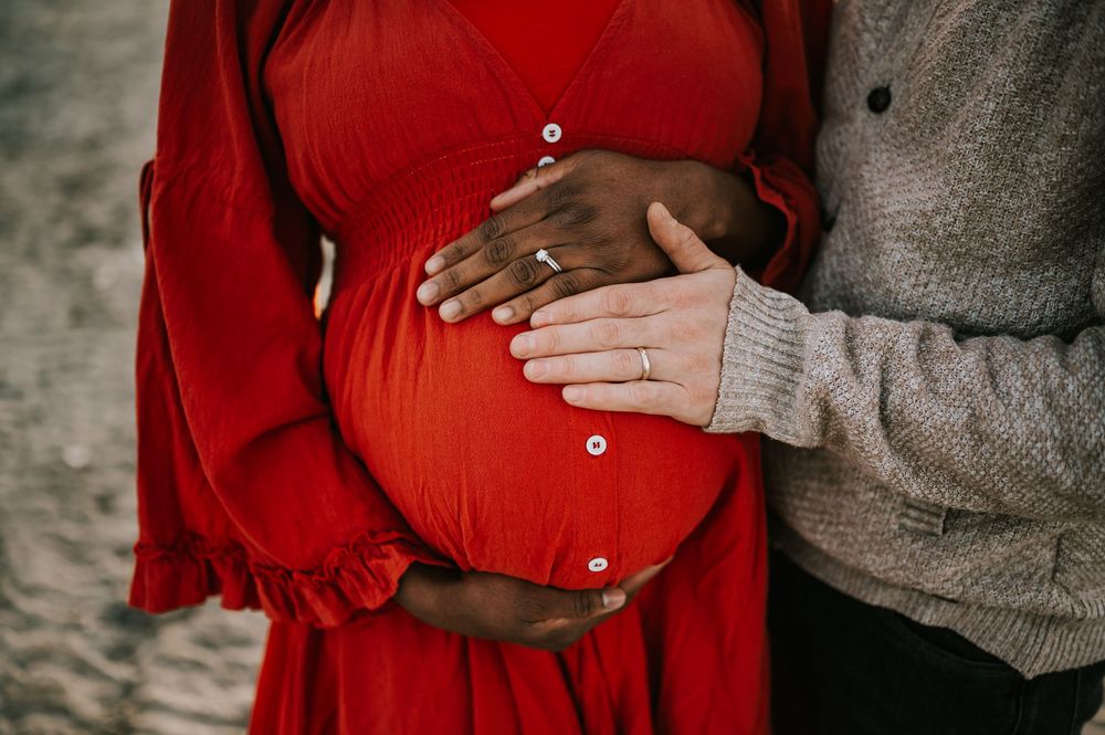 Maternity detail bump shot on kye bay beach in red dress by ocean during sunset Comox Valley Vancouver Island photographer