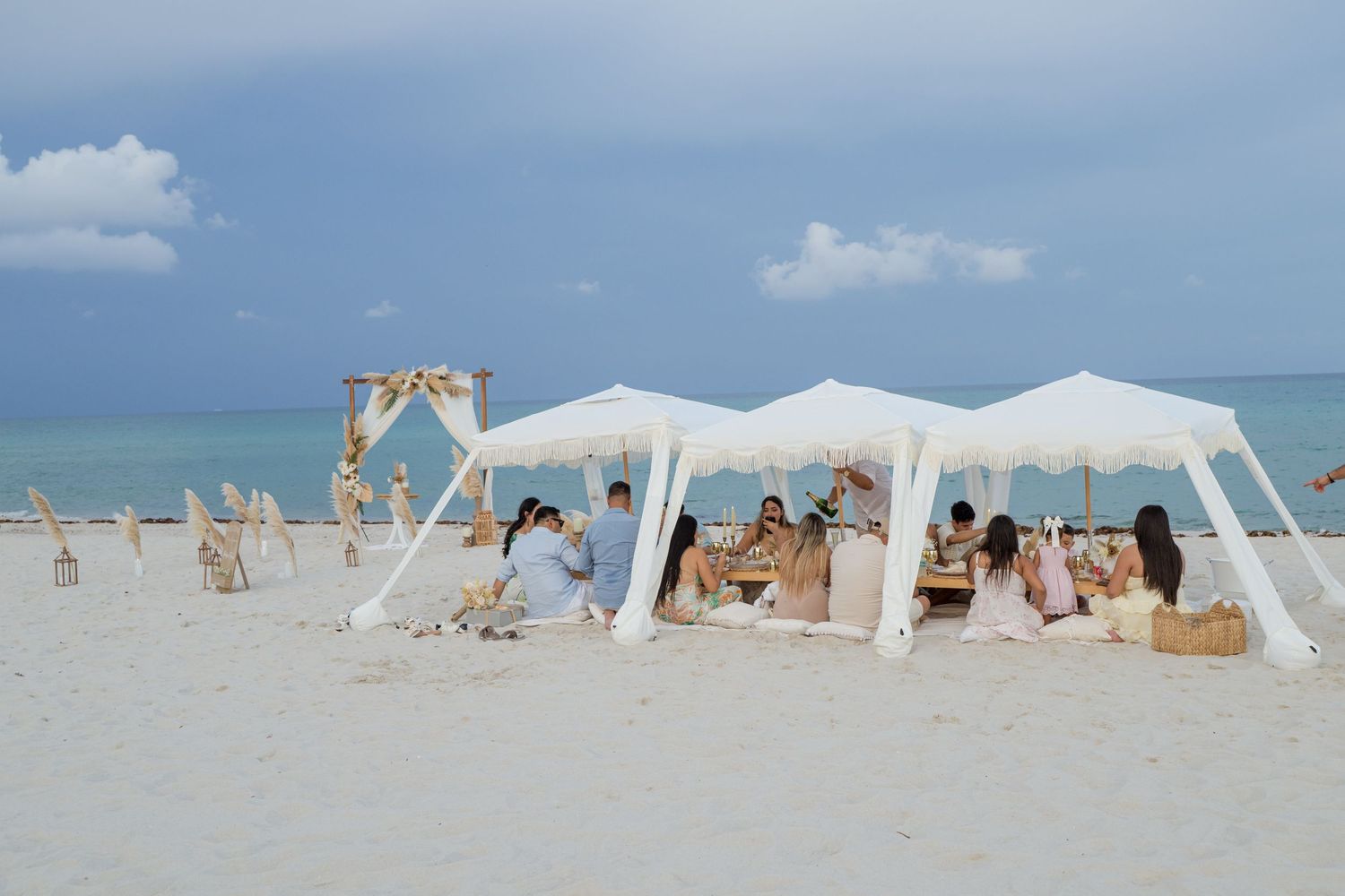 White beach cabanas and umbrellas line a pristine sandy shoreline under blue skies and turquoise waters.