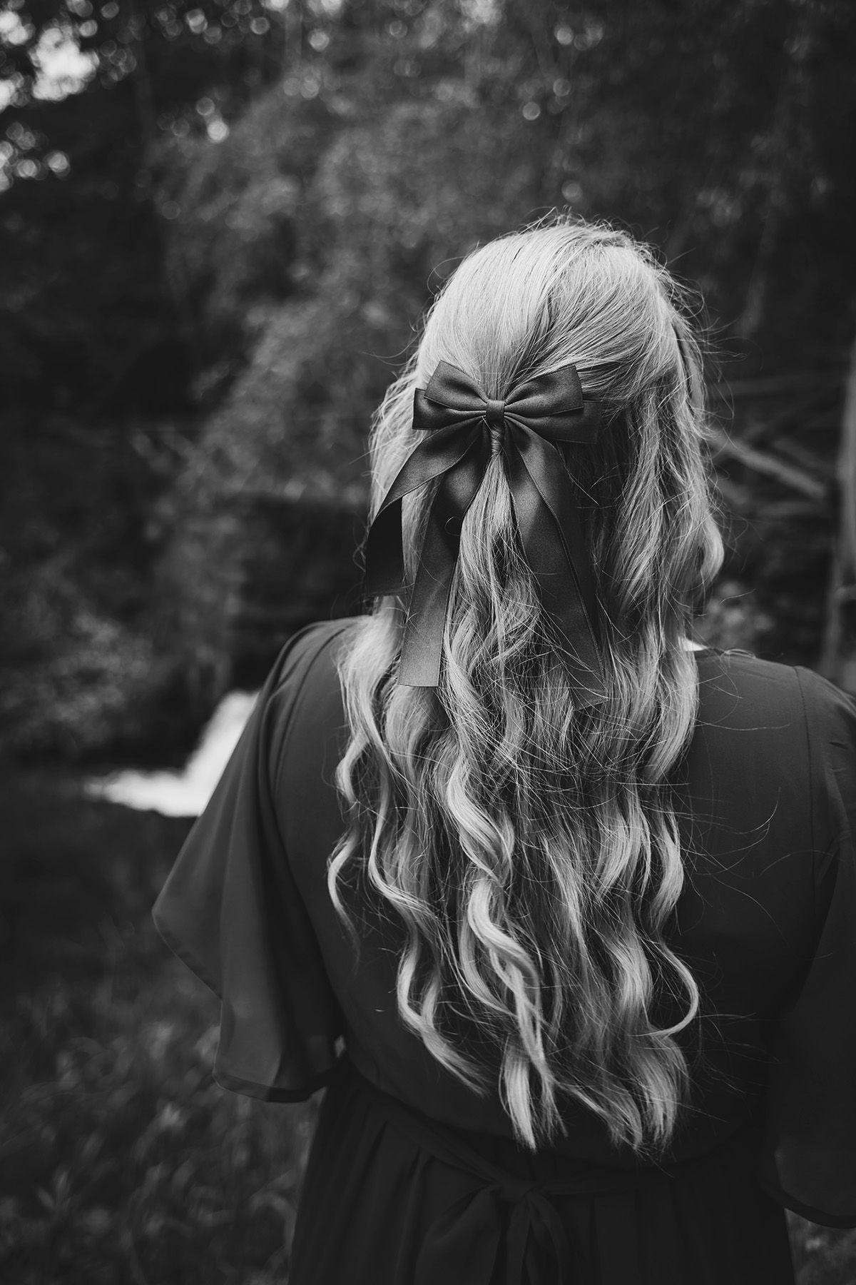 Svartvit bröllopsbild på brud med enkel håruppsättning och rosett – bröllopsinspiration för hårstyling med lockar.