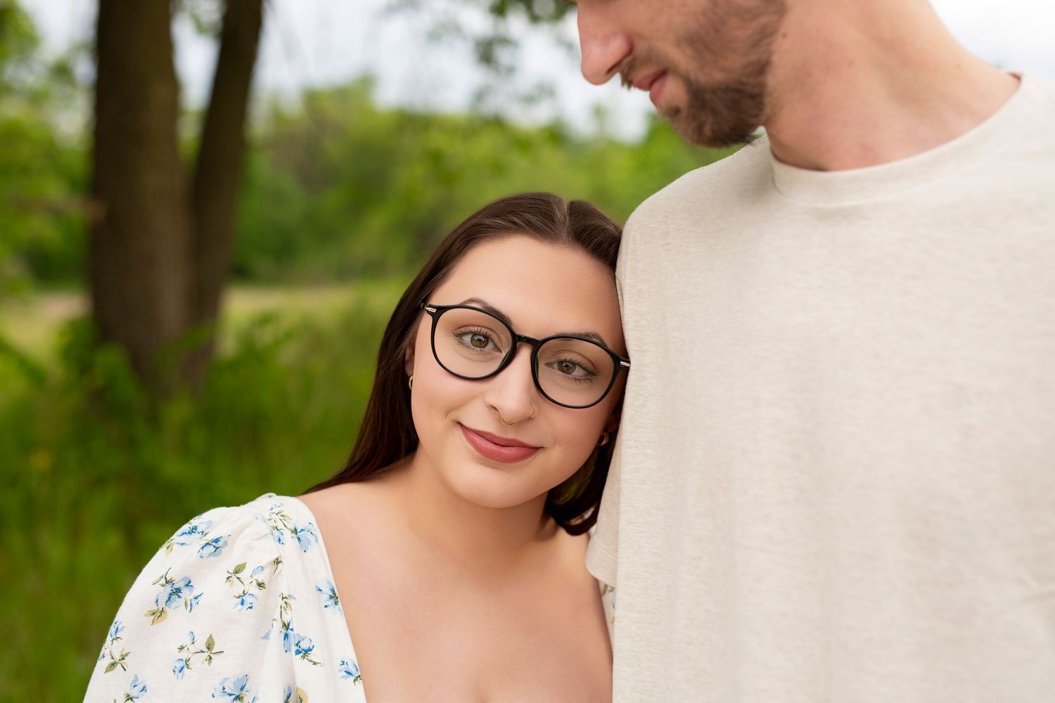 A couple sharing an intimate moment outdoors with green foliage in the background.