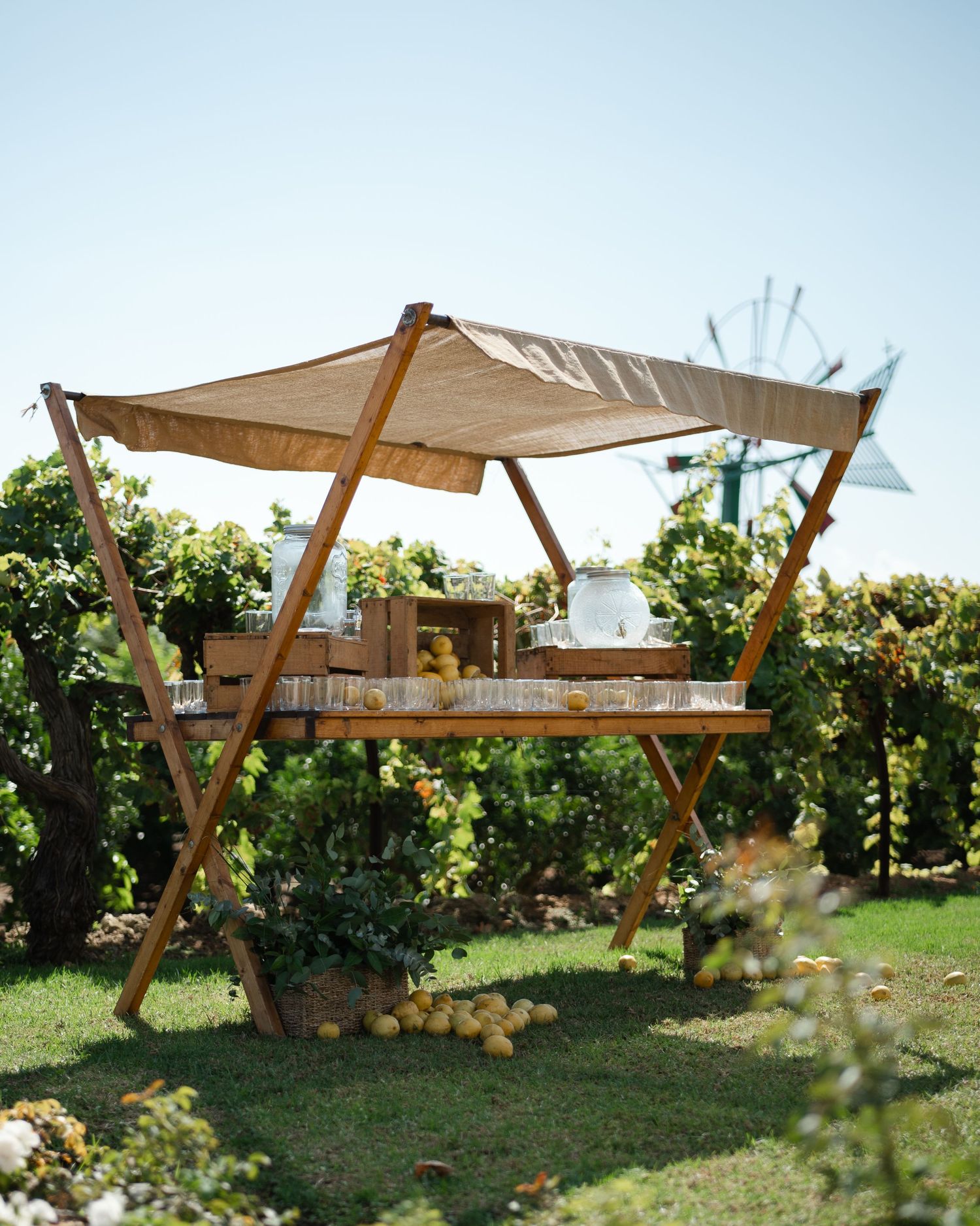 Modern outdoor seating area with wooden canopy structures and shade sails in a lush garden setting.