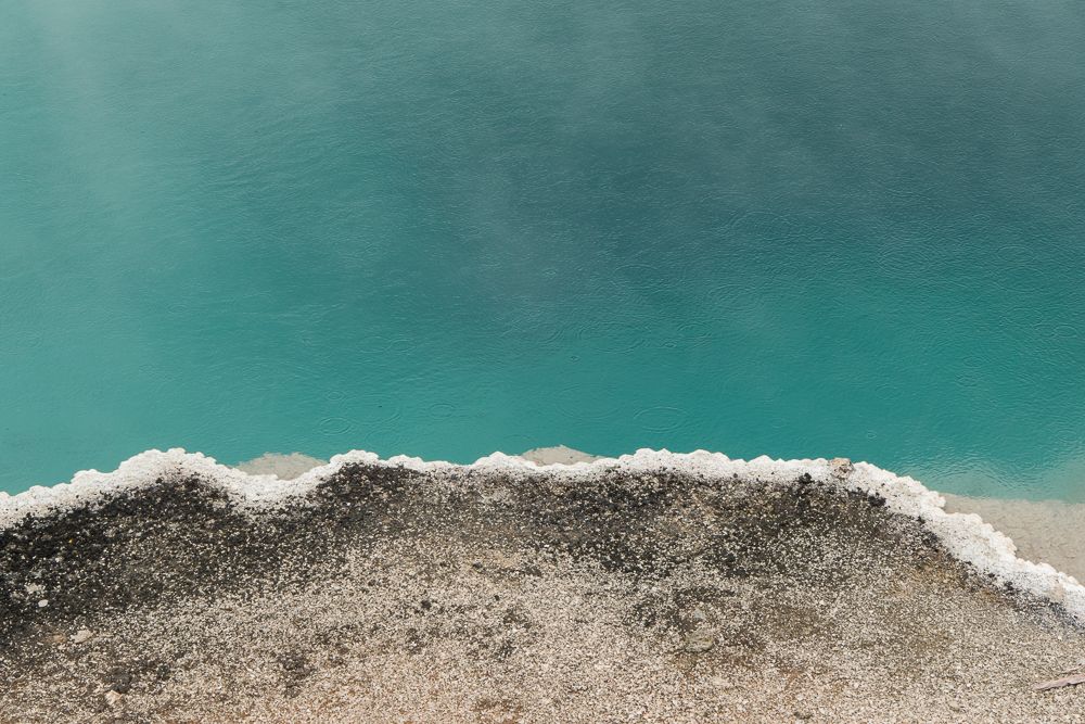 Aerial coastal landscape view of turquoise ocean waters meeting white sandy beach shoreline.