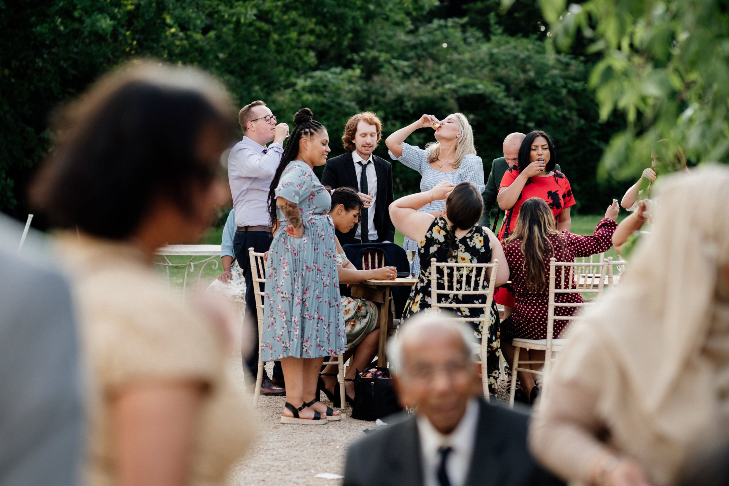 Wedding guests react with emotion during an outdoor garden ceremony with chairs set up on a patio.