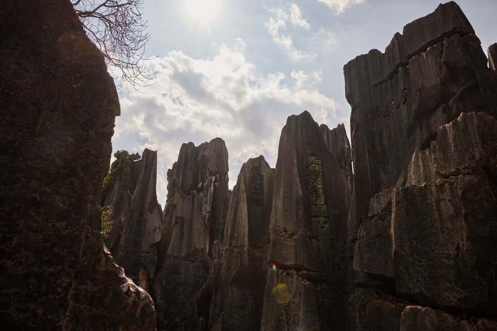 Dramatic stone pillars rise against a cloudy sky at the Shilin Stone Forest limestone karst formation in China.