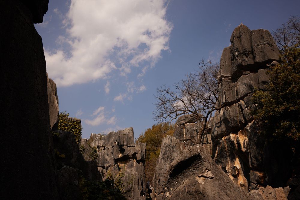 Dramatic rock formations tower against a blue sky with wispy clouds at Externsteine natural monument in Germany.