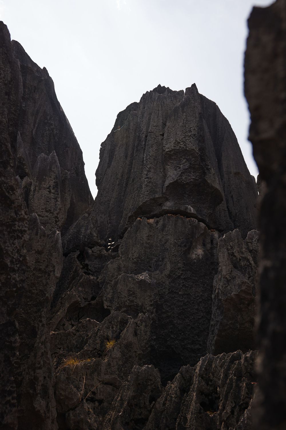Dark atmospheric rock formations tower against a moody sky, showcasing jagged peaks and vertical cliffs.