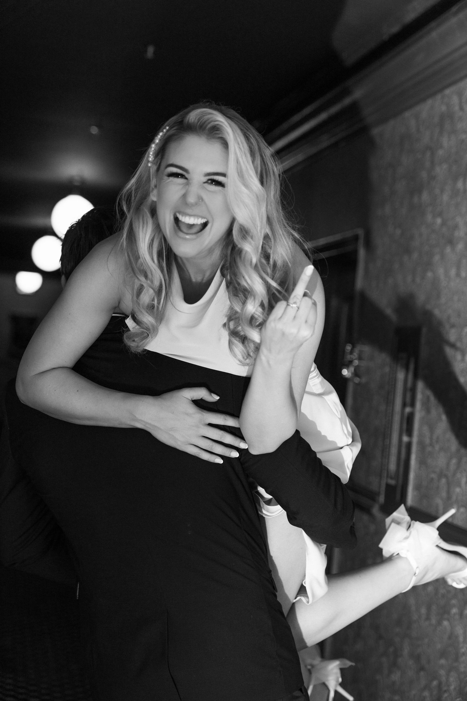 Candid black and white photo capturing laughter and joy in a dark hallway. Engagement Session at The Lafayette Hotel in San Diego. JPPC