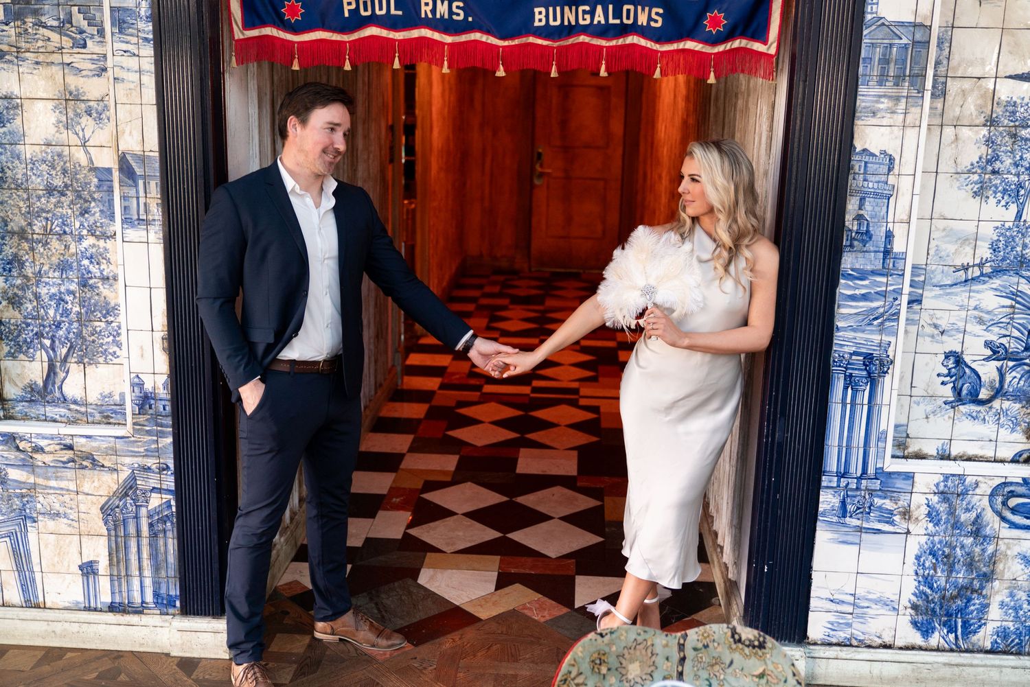 Couple in formal attire standing in front of blue and white tile wall at vintage bungalow entrance. Jessica Paige Photo Co. San Diego.