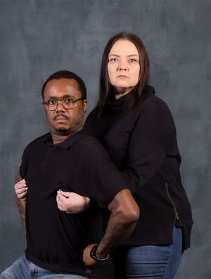 Professional studio photo of two people in black tops posing back-to-back.