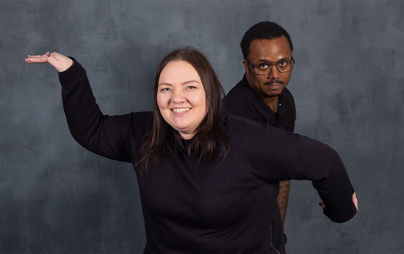 Energetic studio portrait with one person gesturing while another poses behind.