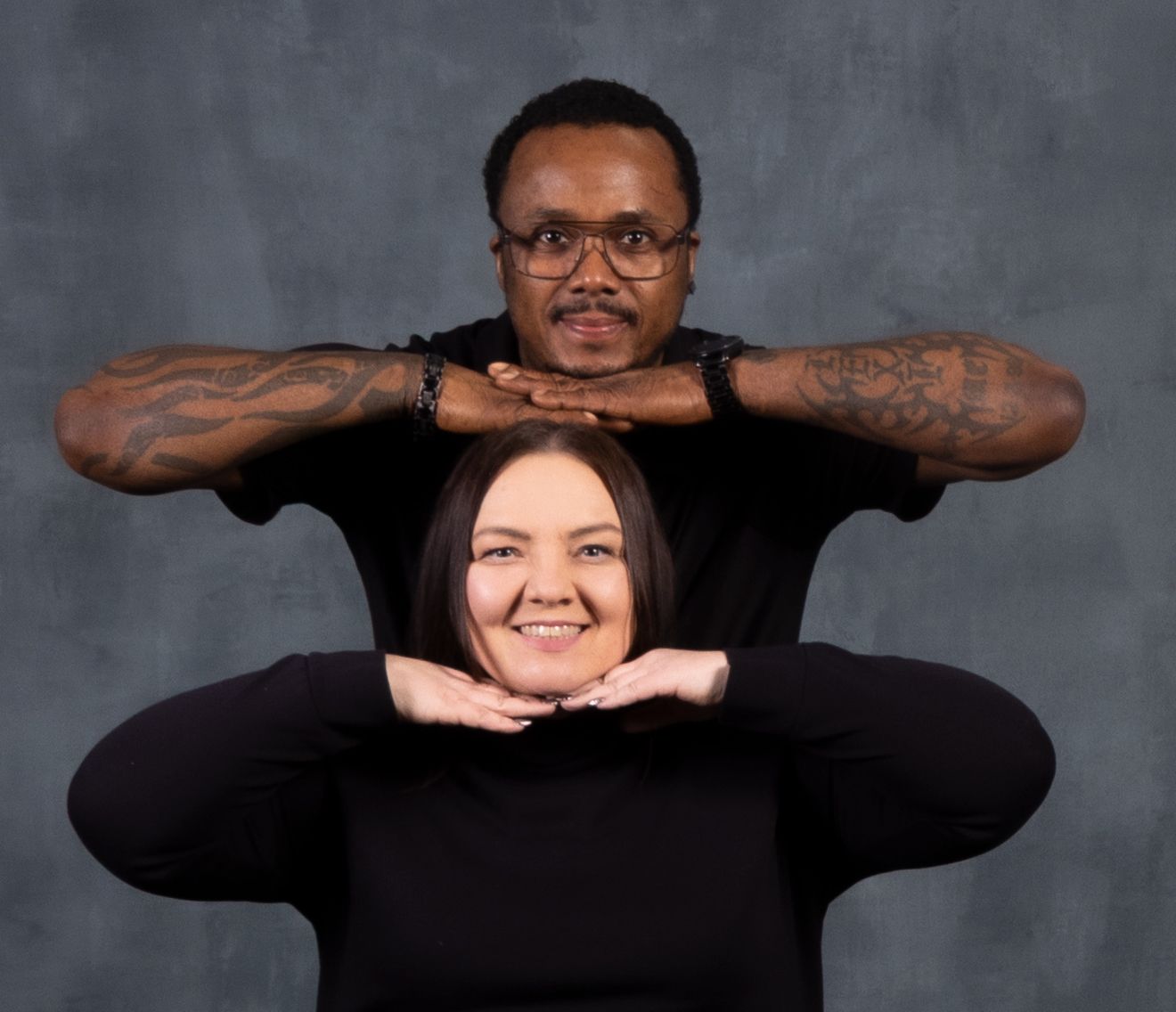 Creative portrait of two people in black clothing posing in a playful framing composition.