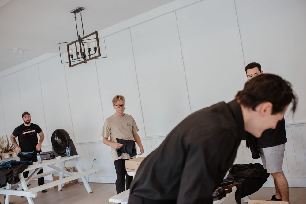 People working out in a bright minimalist gym space with white walls and modern lighting fixtures.