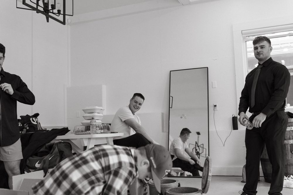 Black and white photograph of a group relaxing together in a minimalist room with white walls and simple furnishings.