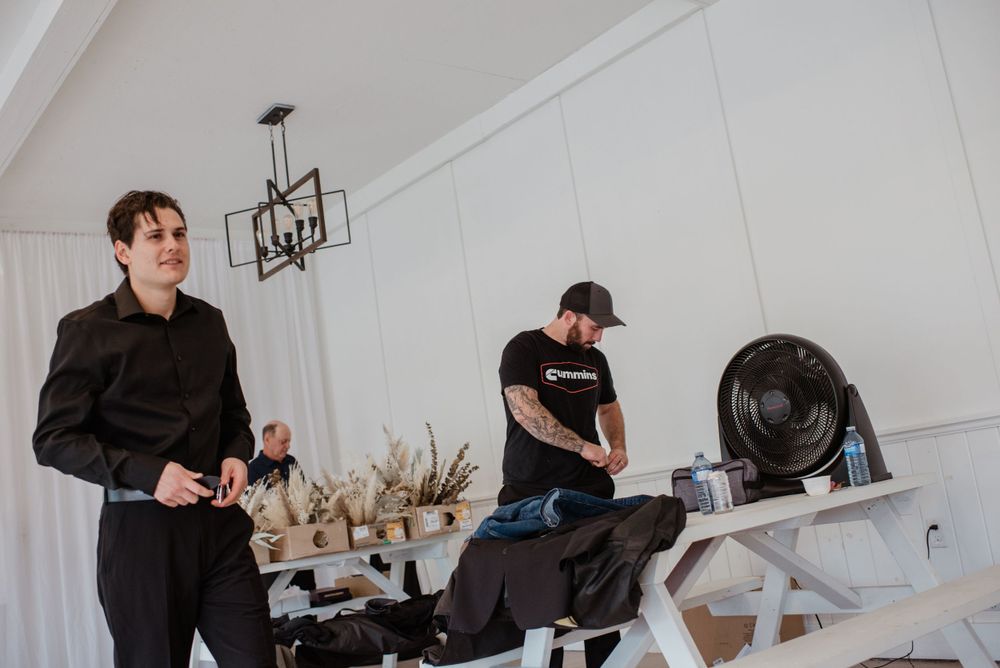 Two massage therapists prepare their equipment at a spa treatment room with white walls and decorative lighting.