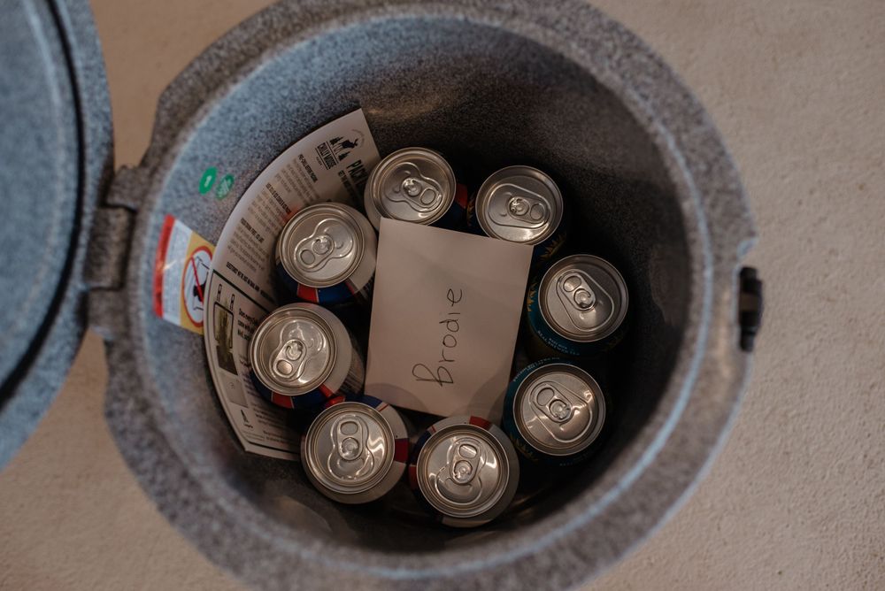 Beer cans arranged in a circular pattern inside a dark cooler with ice.