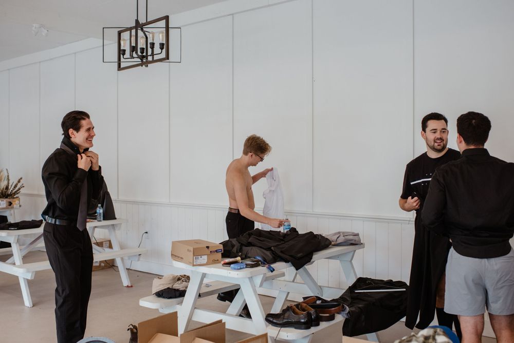 People standing around a white table unpacking boxes and organizing items in a bright minimalist space.