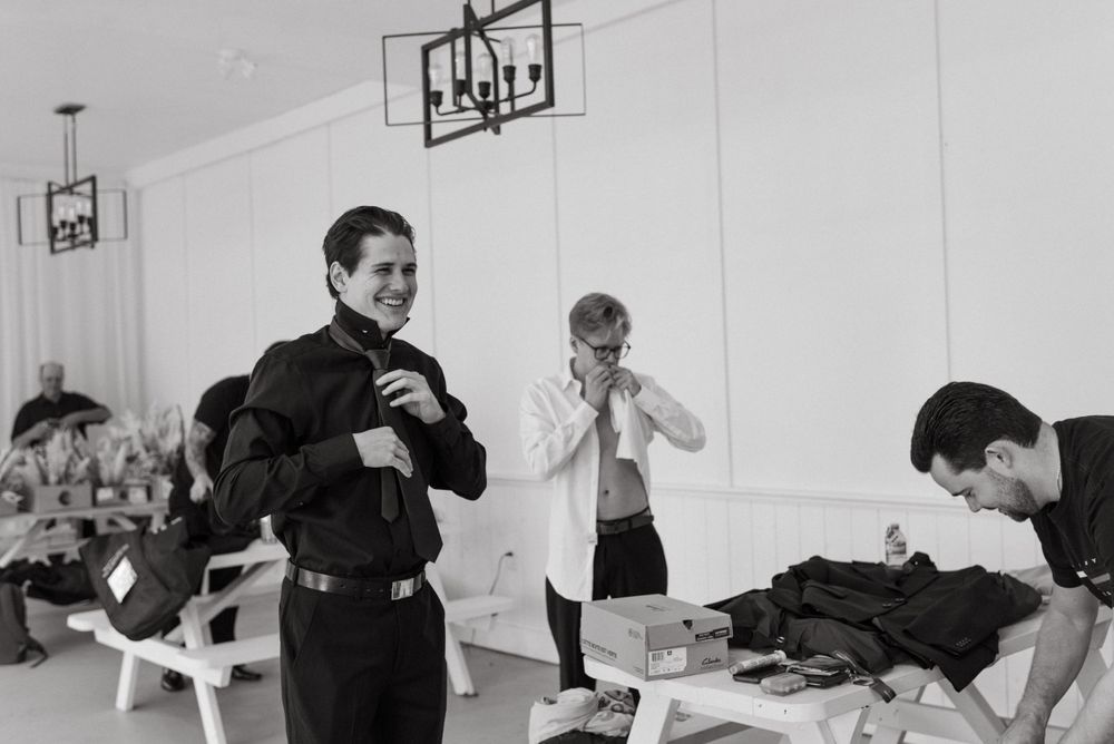 A black and white photo of people in a locker room getting ready, with light fixtures visible on the walls.