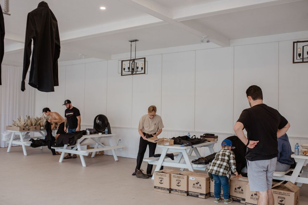 People relax and prepare in a clean, minimalist room with white walls and picnic-style benches.