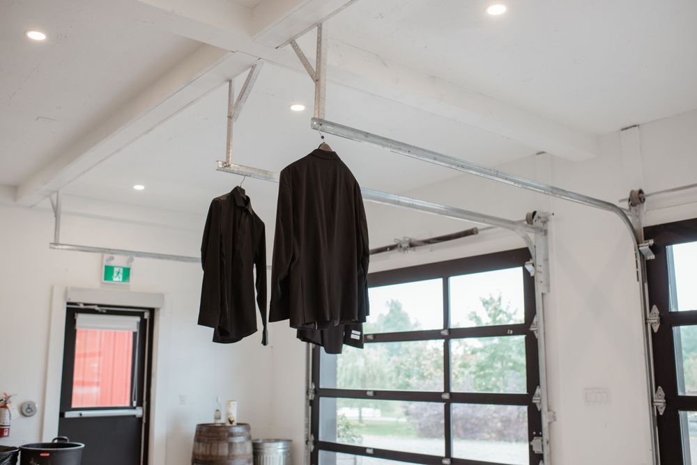 Black jackets hang from an industrial clothing rack against a white wall with windows in a modern space.