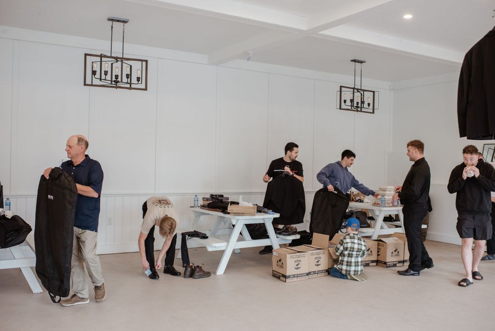 People gather around tables in a minimalist white room with modern pendant lighting fixtures.
