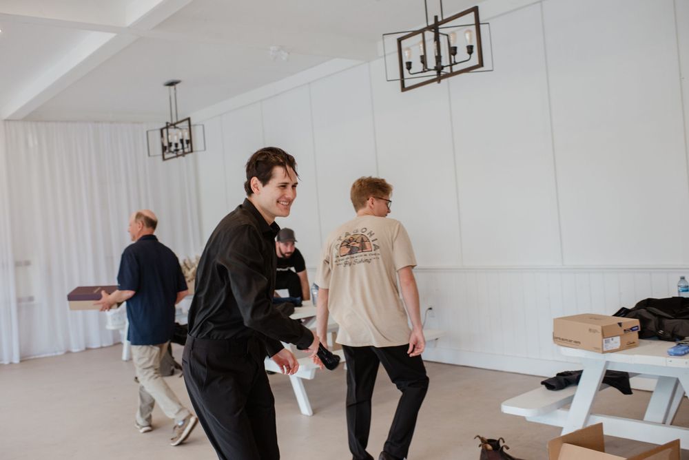 People in casual attire walk through a bright indoor space with pendant lights and white walls.