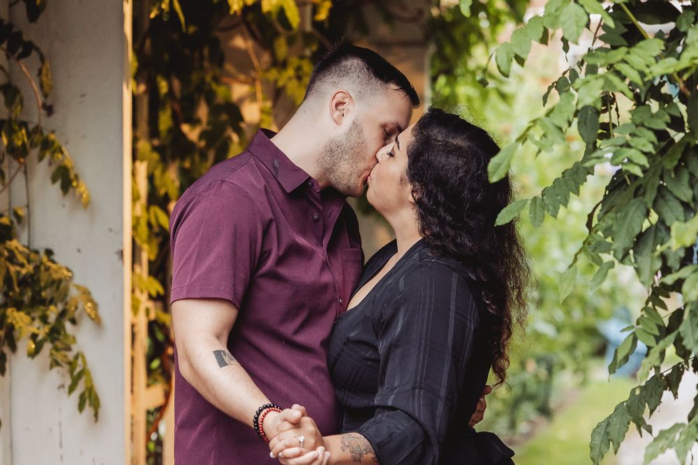 Intimate portrait of couple sharing romantic moment amongst green foliage.