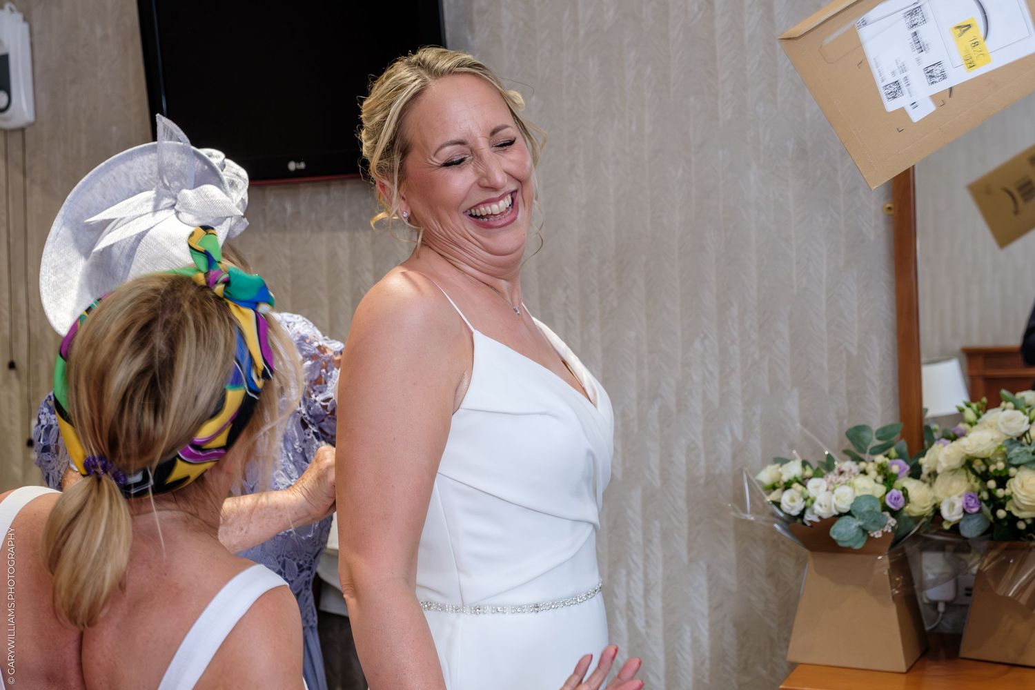 Cheerful wedding party members sharing candid laughs together in elegant white attire.