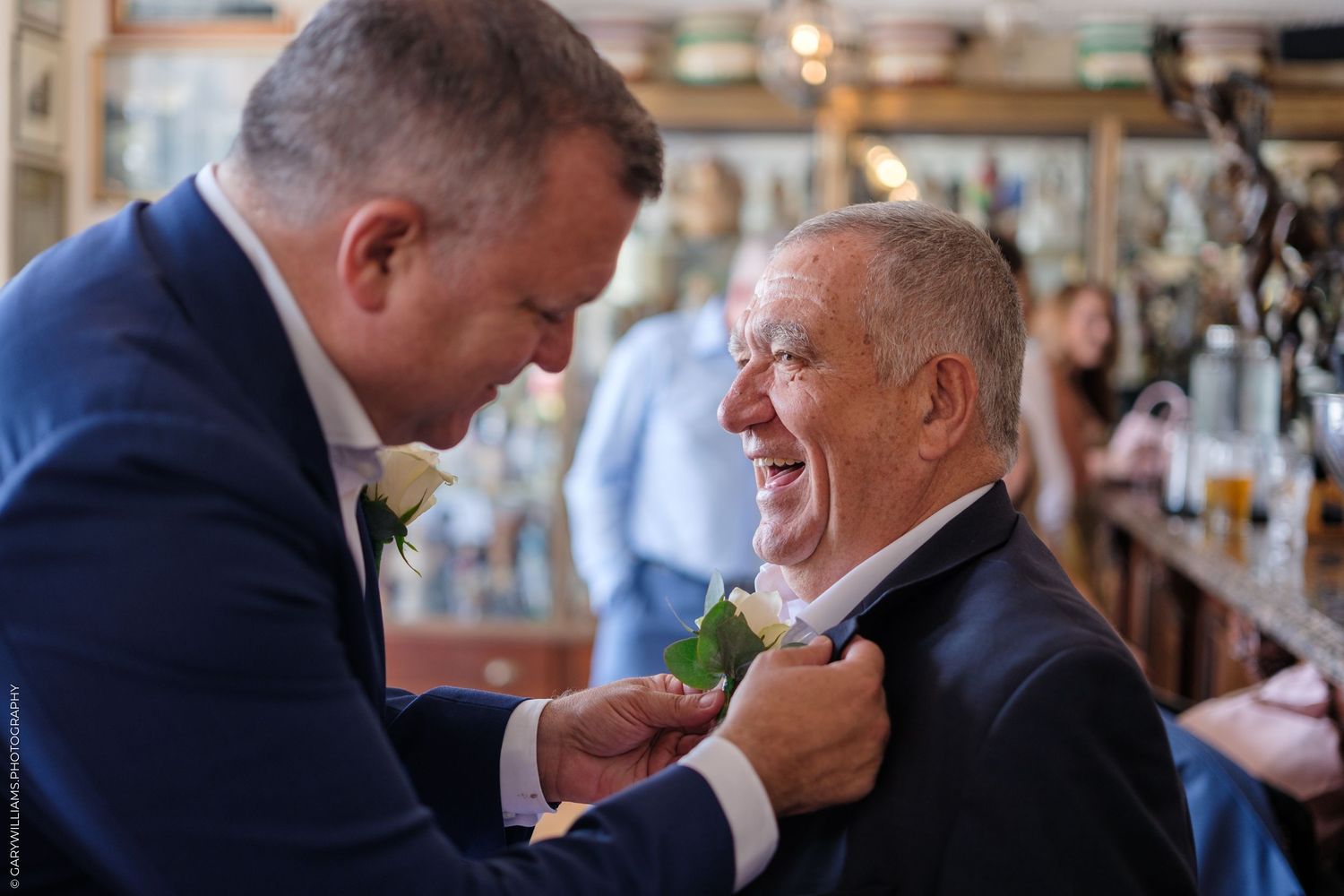 Two people share an emotional hug and embrace during an indoor event at what appears to be a restaurant or party venue.