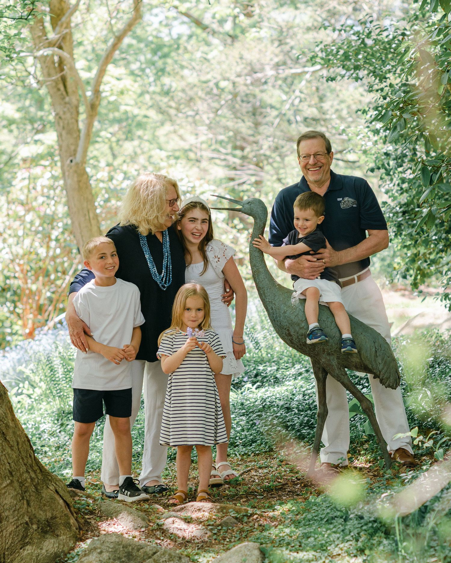 Family enjoying time together on a tree-lined path in a natural outdoor setting during a sunny day.