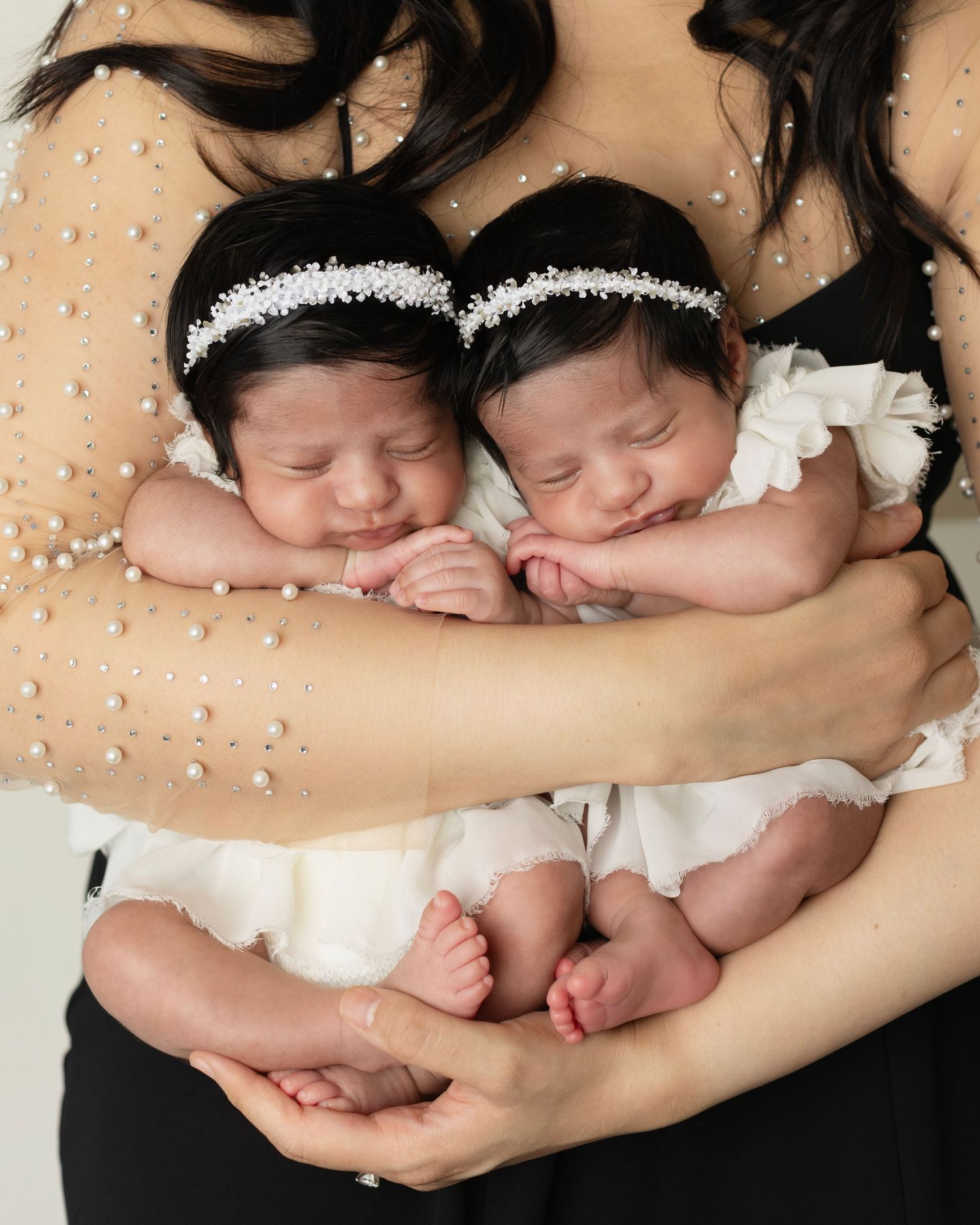 Mom holds twin girls in her arms they sleep snuggles up in tiny white dresses Elizabeth Lang Photography