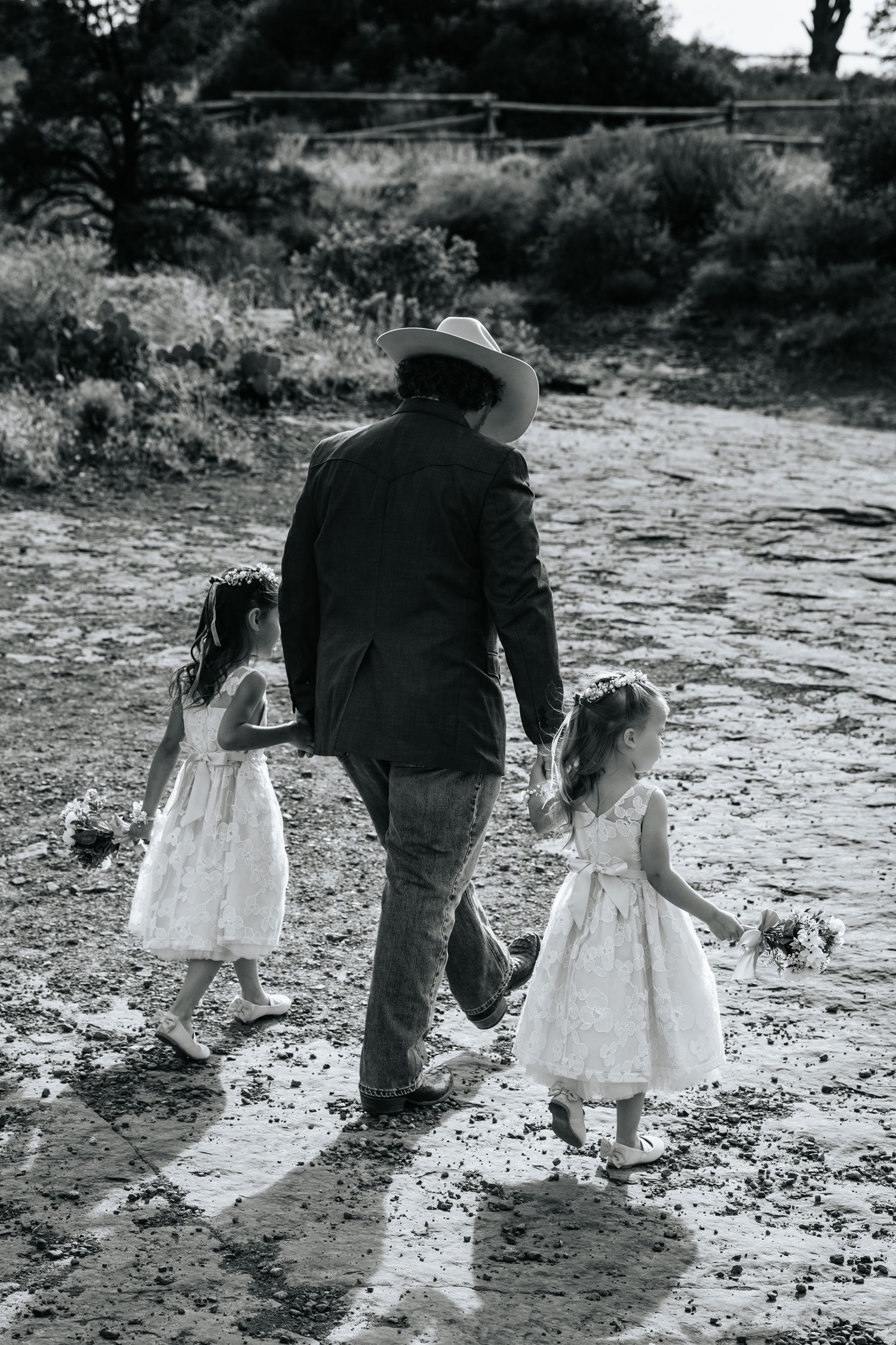 Black and white photo sequence showing adults and children walking together through a natural outdoor setting. Flower girls.