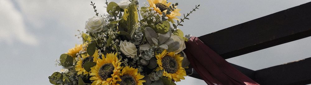 A yellow sunflower bouquet arranged in multiple glass vases on a wooden table in a rustic setting.