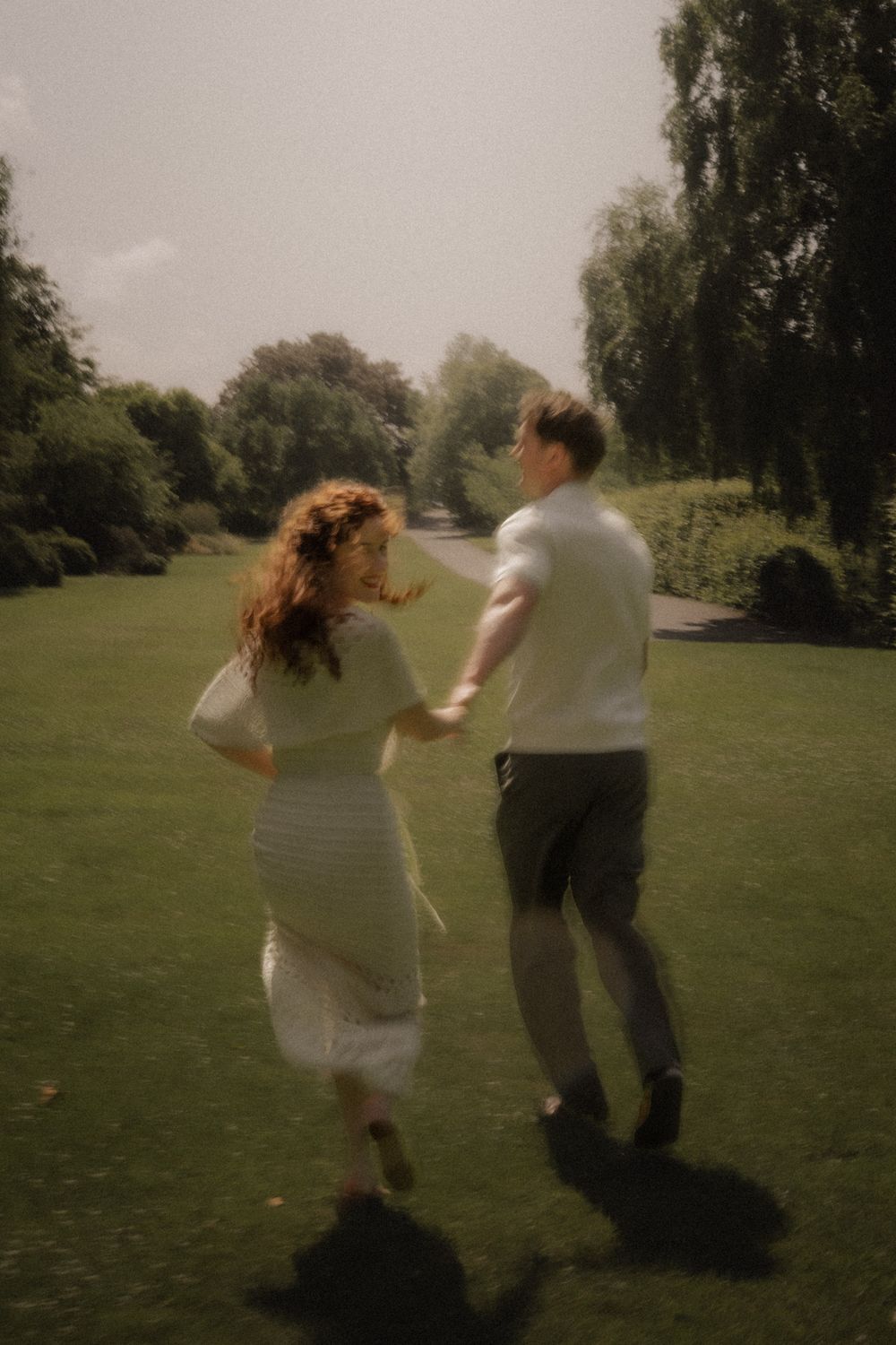 A sequence showing a couple dancing and twirling together on a grassy field with trees in the background.