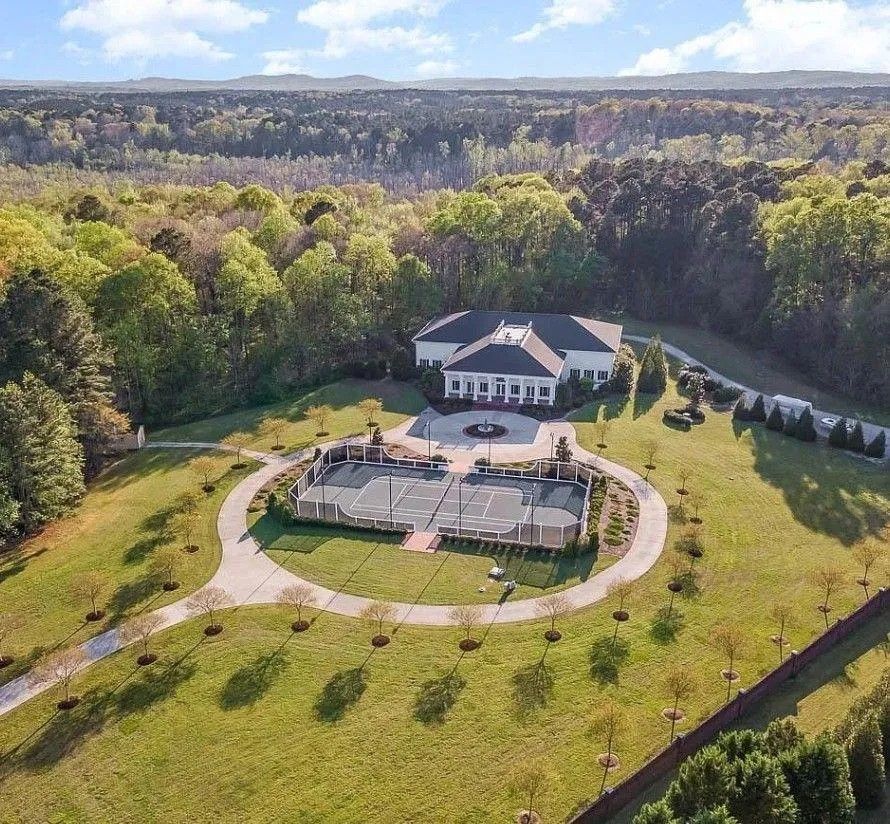 Aerial view of an outdoor amphitheater with stone seating surrounded by autumn trees and forest landscape.