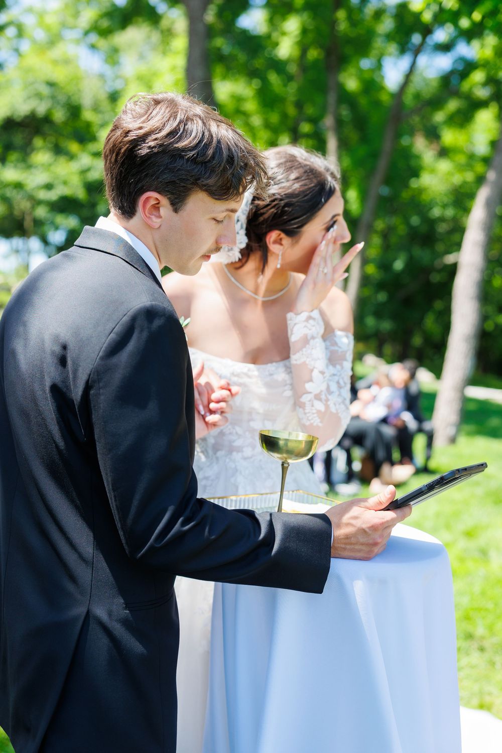 Couple drinking wine at an outdoor unity ceremony during their garden wedding celebration.
