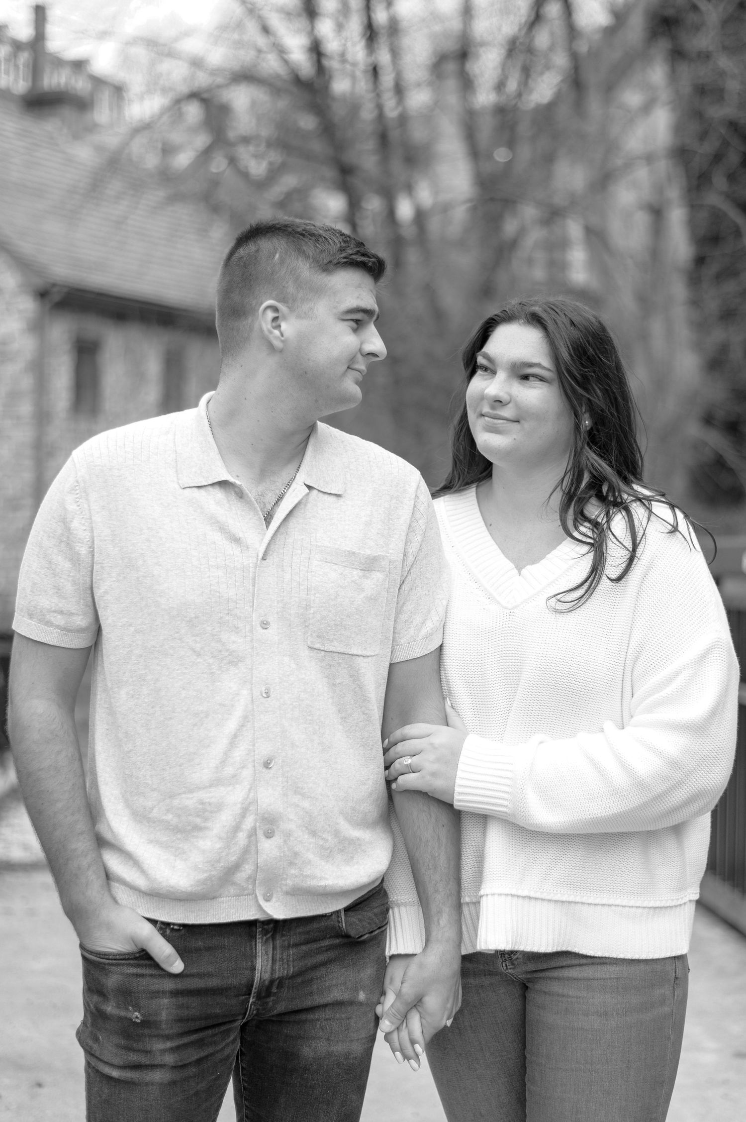 A black and white portrait of a couple sharing a tender moment outdoors.