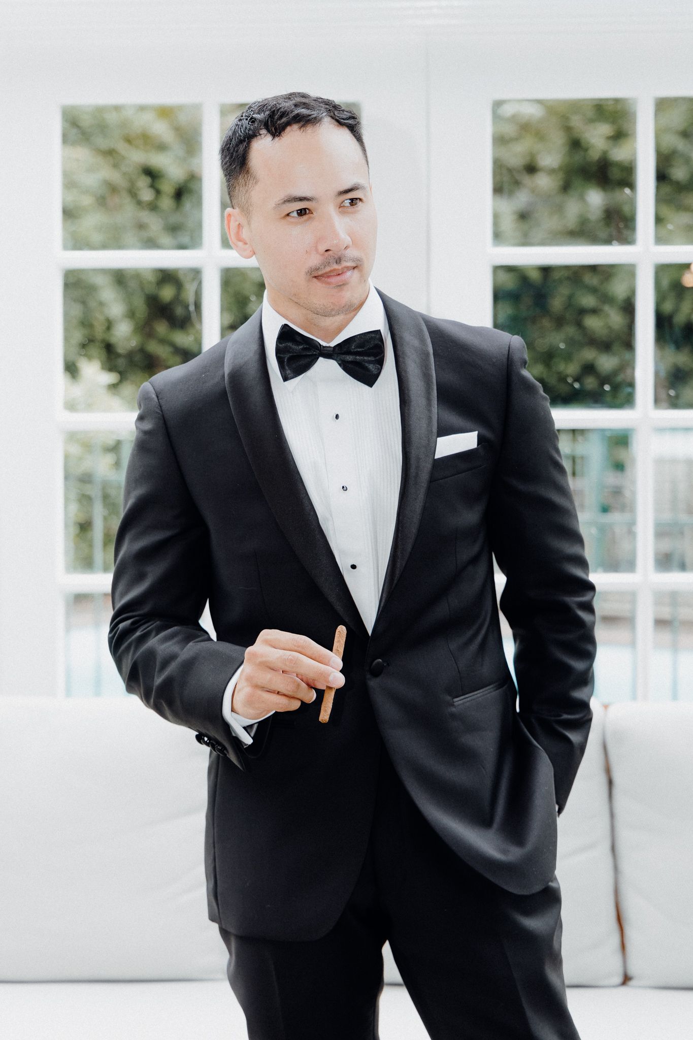 The groom in an elegant black tuxedo with bow tie and crisp white shirt poses captured by Apertured Media Auckland Wedding Photographer.