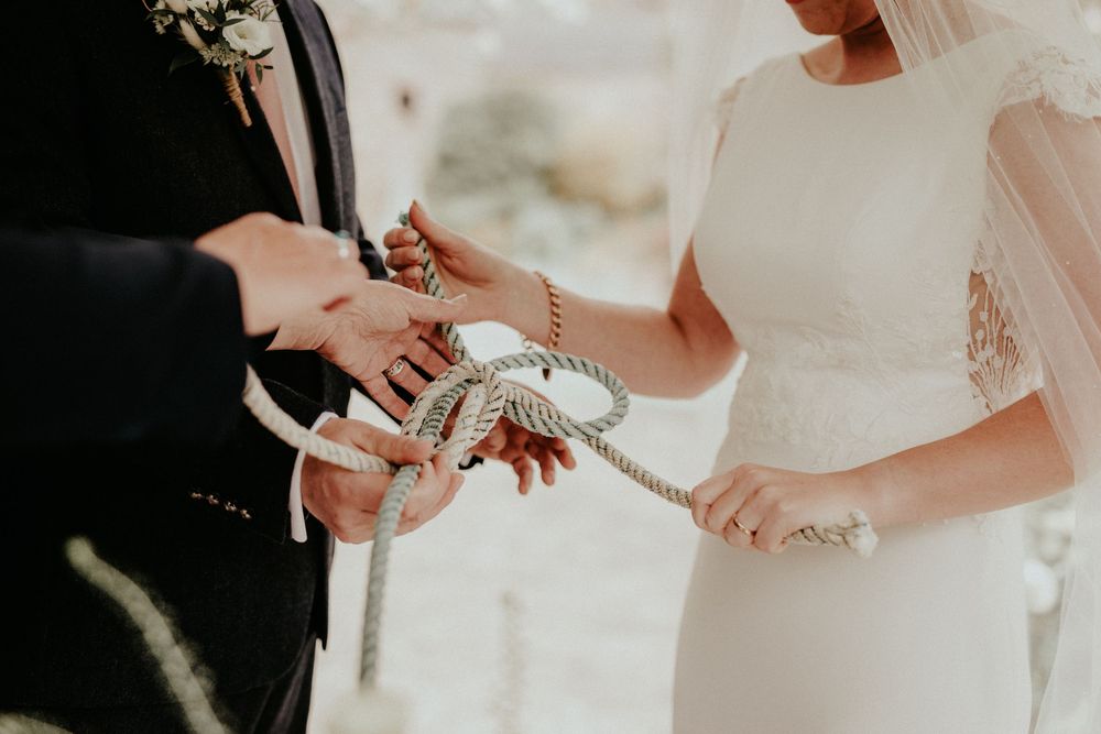 Close-up shot of couple exchanging wedding rings during an intimate outdoor ceremony.