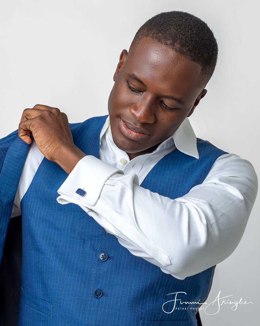 Professional portrait showing a young man wearing a crisp white shirt and blue waistcoat with matching cufflinks