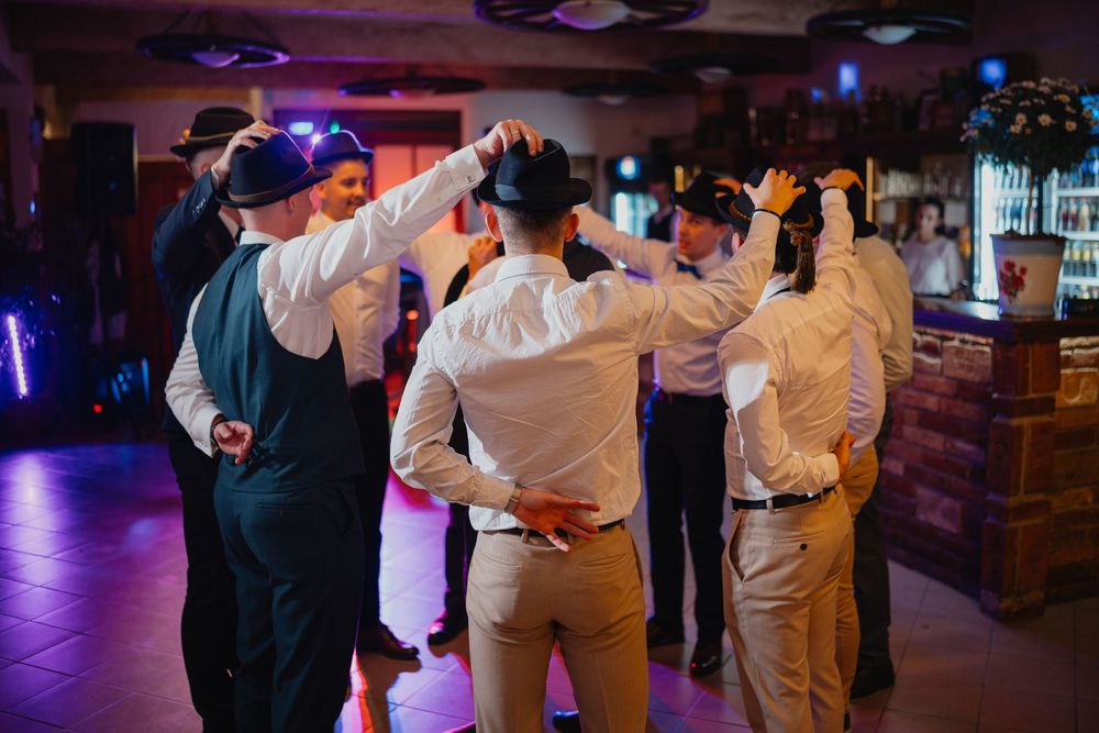 A group of people dancing together in a dimly lit bar with blue lighting and wooden decor.