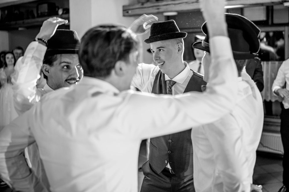A black and white photo showing several men in vintage attire engaged in a spirited dance or celebration.